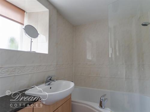 een badkamer met een wastafel, een bad en een spiegel bij Tavern Way in Corfe Castle