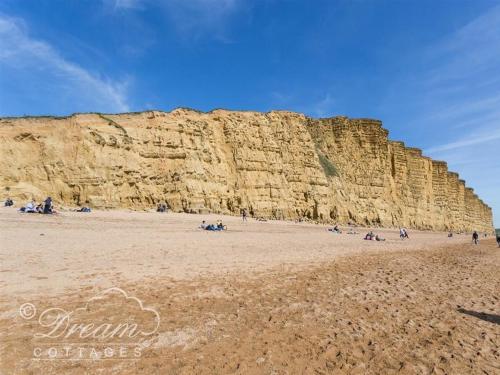 a group of people on a beach next to a cliff at The Wave in West Bay