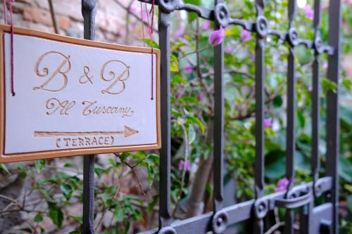 een bord op een metalen hek met bloemen bij Al Tuscany B&B in Lucca
