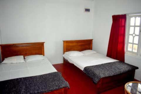 2 camas en una habitación blanca con ventana en Max Mount View en Nuwara Eliya