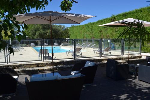 une terrasse avec des chaises et un parasol ainsi qu'une piscine dans l'établissement Camping les Silhols, à Lagorce