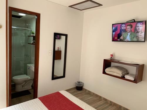 y baño con cama, aseo y espejo. en Hotel Maceo 55 - Colonial Inn, en Bogotá