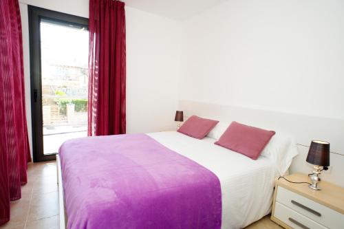 a bedroom with a large bed with purple sheets and a window at S'Arenal Petit in Portocolom