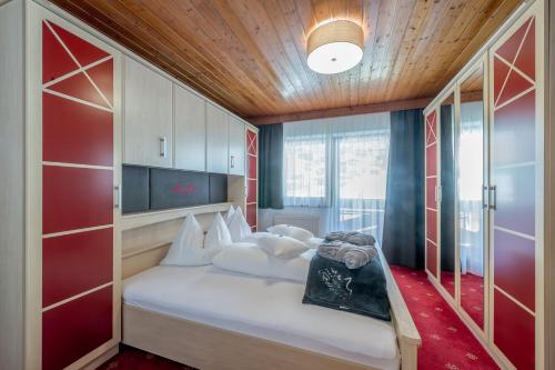 ein Schlafzimmer mit einem Bett mit einer roten Wand in der Unterkunft Hotel Burgstein - alpin & lifestyle in Längenfeld