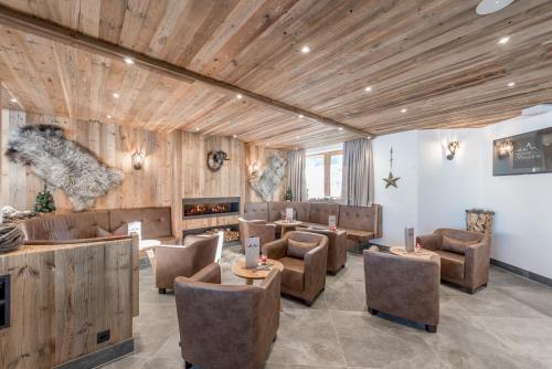 eine Lobby mit Stühlen, Tischen und einem Kamin in der Unterkunft Hotel Burgstein - alpin & lifestyle in Längenfeld