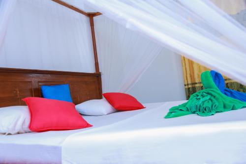 a bed with red and blue pillows on it at Sajana Ocean Hill in Mirissa