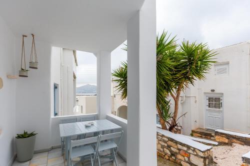 a white balcony with a table and a palm tree at PEBBLES 1BD house with Sea View in the heart of Naousa in Naousa