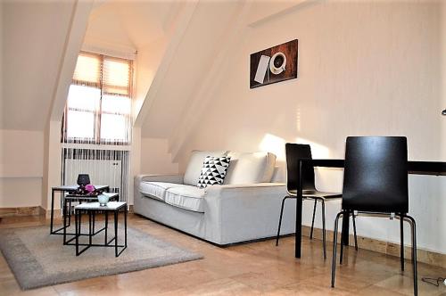 sala de estar con sofá blanco y sillas negras en Downtown Apartments Superior, en Győr