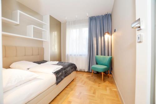 a bedroom with two beds and a green chair at Apartamenty MIZU - "Marmur" in Kołobrzeg