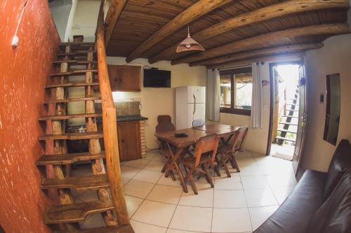 a kitchen and dining room with a wooden spiral staircase at Pousada Pé na Areia in Garopaba