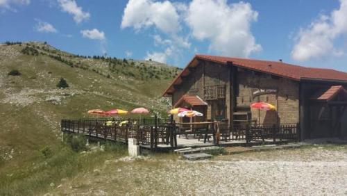 a building with tables and umbrellas on a hill at Le p'tit Cozy in Le Dévoluy