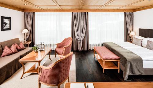 a hotel room with a bed and a couch at Hotel Alpenroyal - The Leading Hotels of the World in Selva di Val Gardena