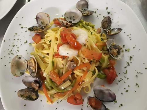 a white plate of food with pasta and vegetables at Hotel Des Alpes in Rosta