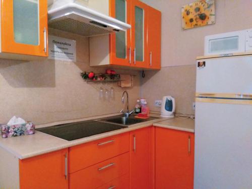 ペンザにあるApartment Na Rakhmaninova 5のキッチン(オレンジ色のキャビネット、シンク、冷蔵庫付)