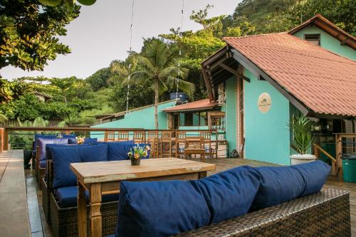 une terrasse avec des canapés bleus et une table en bois dans l'établissement Pousada Reserva do Tombo Lounge Hostel, à Guarujá