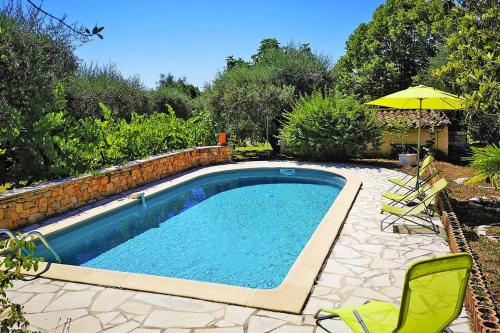 a swimming pool with two chairs and an umbrella at Ma Vie La in Fayence
