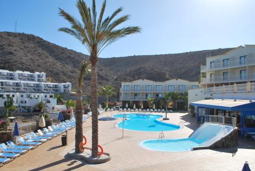 un complejo con piscina y palmeras en Apartamentos Natural Park, en Puerto Rico de Gran Canaria