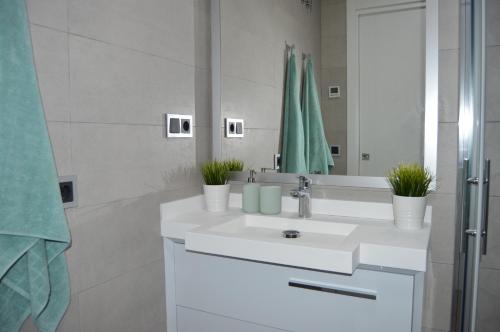 een witte badkamer met een wastafel en een spiegel bij Sunset Drive Paradise - Benidorm in Benidorm