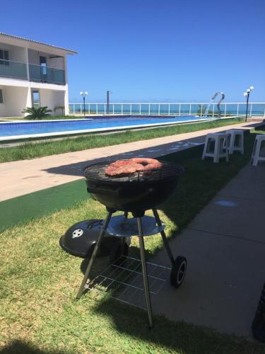 a barbecue grill sitting next to a swimming pool at Dúplex/bangalô em Jacuma in Jacumã