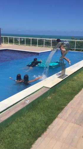 a group of people in a swimming pool at Dúplex/bangalô em Jacuma in Jacumã