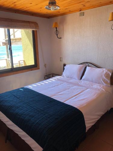 a bedroom with a large bed with white sheets and a window at Delfín Apart in Pichilemu