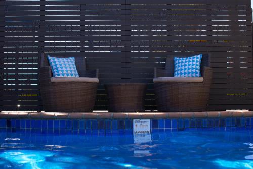 Duas cadeiras com almofadas ao lado de uma piscina em Tuncurry Motor Lodge em Tuncurry