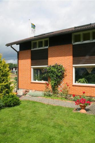 a brick house with a green lawn in front of it at Rähni Maja in Põlva