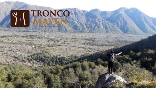 a person standing on top of a rock on a mountain at Cabañas Tronco Mayen in Las Trancas