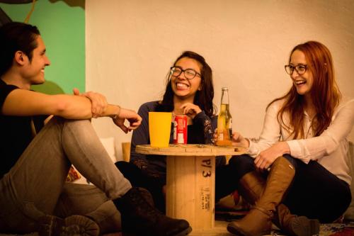 eine Gruppe von drei Personen, die mit Getränken am Tisch sitzen in der Unterkunft Bababuy Hostel in Bogotá