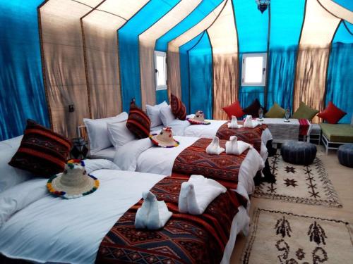 a bedroom with three beds with dolls on them at Starry Desert Nights Camp in Merzouga
