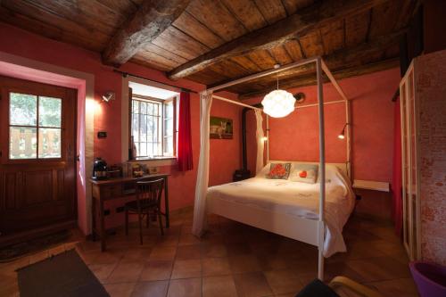 カンネロ・リヴィエーラにあるla vecchia casa rosaのベッドルーム(天蓋付きベッド1台、デスク付)