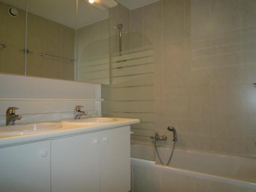 ein Badezimmer mit zwei Waschbecken, einer Badewanne und einem Spiegel in der Unterkunft Residentie Albert-1, app.202, Zeelaan 214 in De Panne