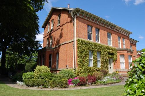 um edifício de tijolos vermelhos com hera em Cornerstones Guest House em Sale