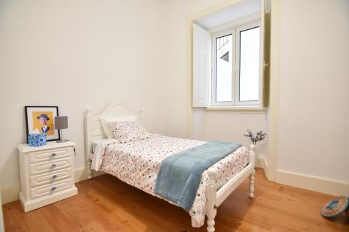 a white bedroom with a bed and a window at Casa Pé da Cabra in Coimbra