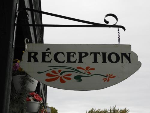 a sign that reads reception hanging from a building at Hôtel Sous la Croix 152725 in Tadoussac