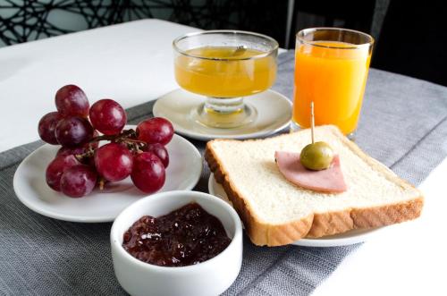 a table with a plate of toast and fruit and orange juice at Sunec Hotel in Chiclayo