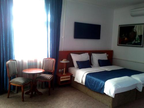 Habitación de hotel con cama, mesa y sillas en Hotel Leotar en Trebinje