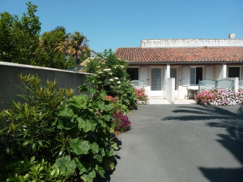a house with a garden with flowers and a fence at Chambres d'Hôtes L'Insulaire in Saint-Denis-dʼOléron