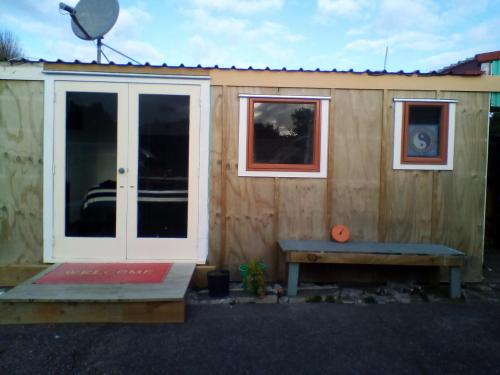 a tiny house with a door and a bench at Ironsands B&B Studio Unit in Patea