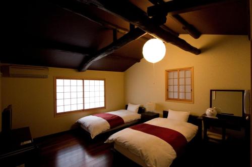 a bedroom with two beds and two windows at Akane an Machiya House in Kyoto
