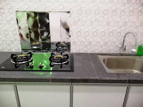 a kitchen counter with a sink and a mirror at NAZ Homestay in Jitra