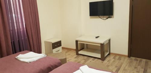 a room with two beds and a desk and a television at B&B Europa Hotel in Kutaisi