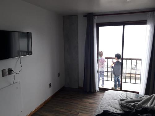 two children standing in a room looking out the window at Eco Nautic Hostel in Valdivia