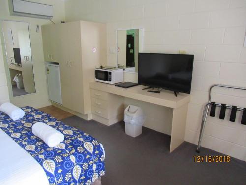 a bedroom with a desk with a tv and a bed at Moruya Motel in Moruya