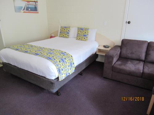 a bed and a chair in a room with a bed and a couch at Moruya Motel in Moruya
