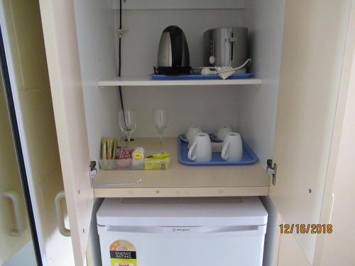 a small refrigerator with a shelf above it at Moruya Motel in Moruya