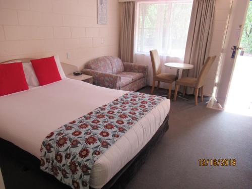 a hotel room with a bed and a chair at Moruya Motel in Moruya