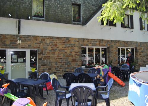 a group of tables and chairs in front of a brick building at Hotel Beco in Banneux
