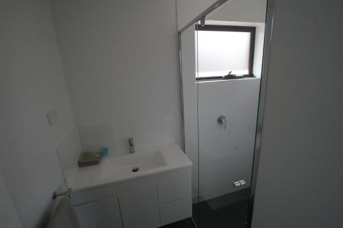a white bathroom with a sink and a shower at Cedar Cottages Blackmans Bay in Kingston