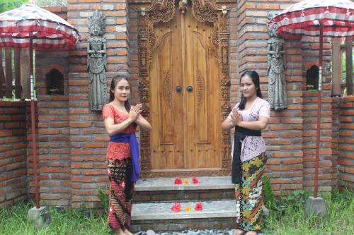 two women standing in front of a wooden door at Halumba Eco Villa Bali in Tejakula